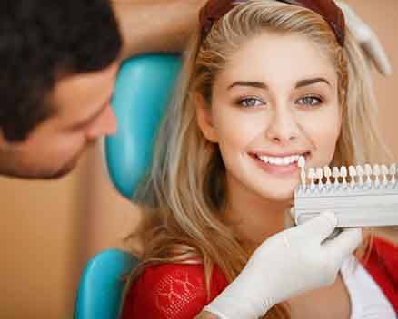 Dentist holding shade guide next to patient’s teeth