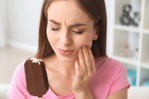 Woman eating ice cream, cringing because of dental sensitivity